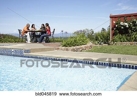 Multi-ethnic couples sitting at outdoor table View Large Photo Image Stock Photo - Multi-ethnic couples sitting at outdoor table. Fotosearch