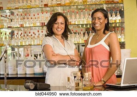 Stock Image - Multi-ethnic female sales clerks at perfume store. Fotosearch
