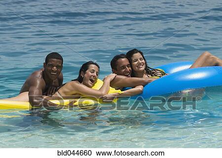 Multi-ethnic friends on floats in water View Large Photo Image Stock Image - Multi-ethnic friends on floats in water. Fotosearch