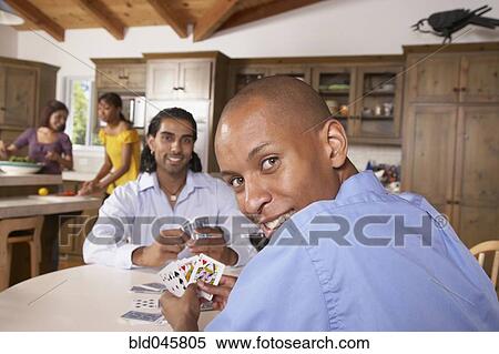 Stock Photography - Multi-ethnic friends playing cards. Fotosearch
