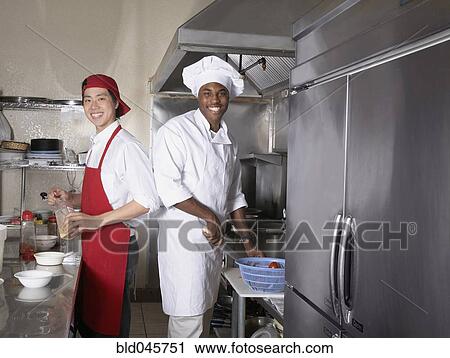Stock Image - Multi-ethnic male chefs preparing food. Fotosearch