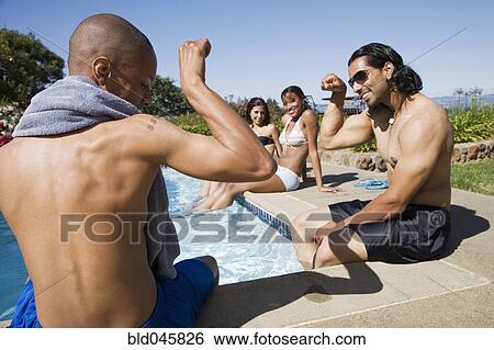 Stock Photograph - Multi-ethnic men flexing at swimming pool. Fotosearch