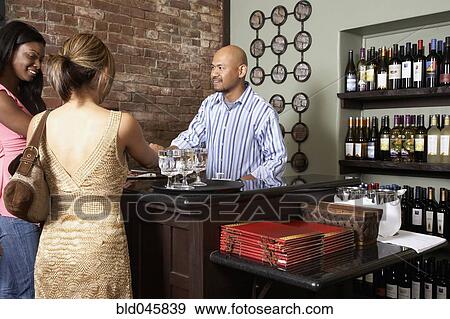 Stock Photo - Multi-ethnic women paying at restaurant. Fotosearch