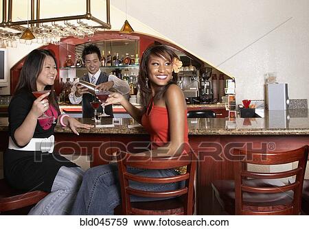 Multi-ethnic women sitting at bar View Large Photo Image Stock Photo - Multi-ethnic women sitting at bar. Fotosearch