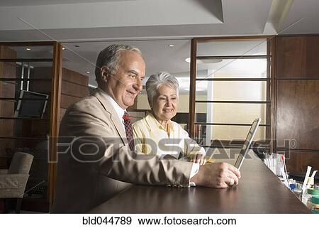 Senior Hispanic businesspeople looking at laptop View Large Photo Image Stock Photo - Senior Hispanic businesspeople looking at laptop. Fotosearch