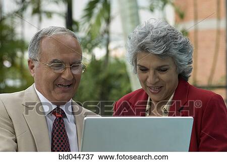 Senior Hispanic couple looking at laptop View Large Photo Image Stock Photo - Senior Hispanic couple looking at laptop. Fotosearch