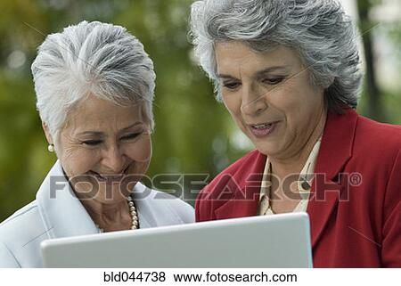 Senior Hispanic women looking at laptop View Large Photo Image Stock Photo - Senior Hispanic women looking at laptop. Fotosearch
