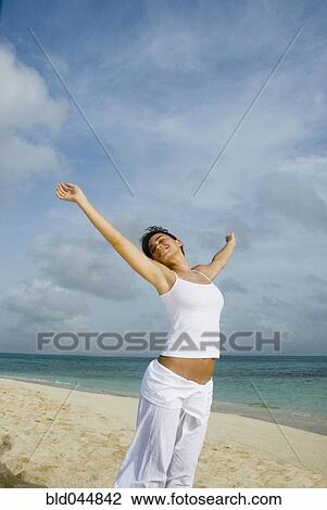 Woman with arms raised at beach View Large Photo Image Stock Image - Woman with arms raised at beach. Fotosearch