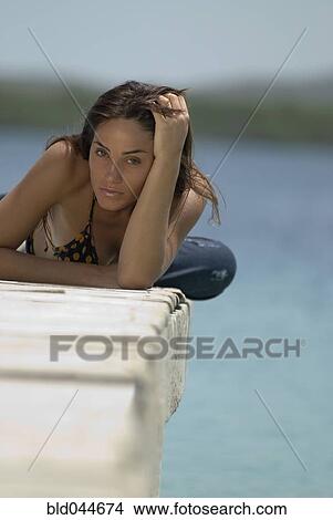 Picture - Young woman laying on dock. Fotosearch