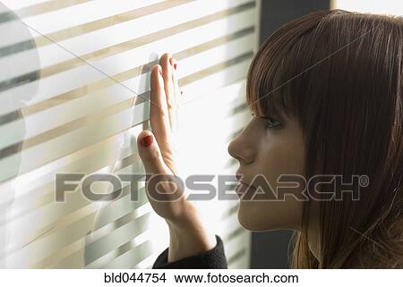 Picture - Young woman looking through frosted glass. Fotosearch