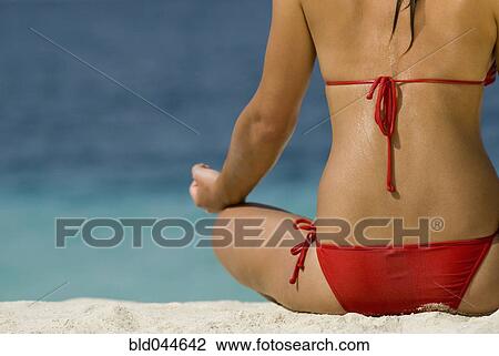 Stock Image - Young woman meditating at beach. Fotosearch