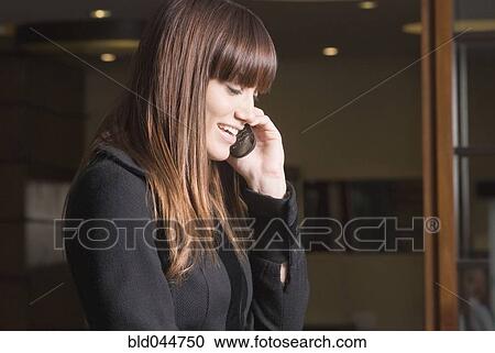 Stock Image - Young woman talking on cell phone. Fotosearch