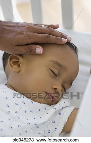 Stock Photo - African American baby sleeping in crib. Fotosearch