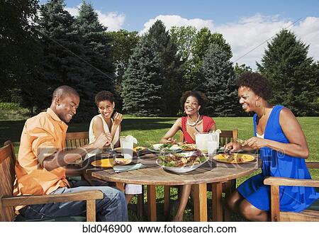 Stock Image - African American friends eating outdoors. Fotosearch