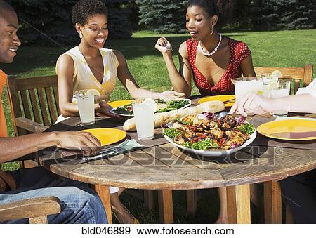 Stock Photo - African American friends eating outdoors. Fotosearch