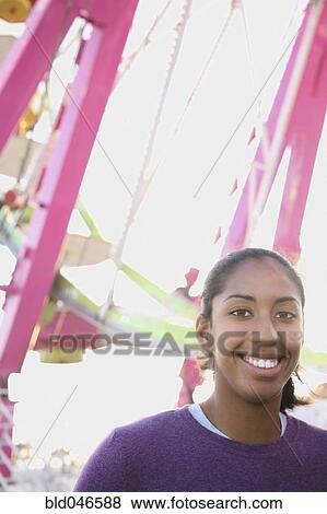 Stock Photo - African American girl in front of Ferris wheel. Fotosearch