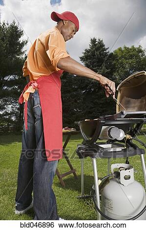 Stock Photograph - African American man barbecuing. Fotosearch