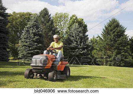 Stock Photograph - African American man mowing lawn. Fotosearch
