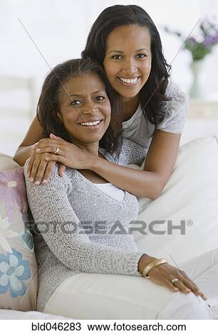 Stock Image - African American mother and adult daughter hugging. Fotosearch