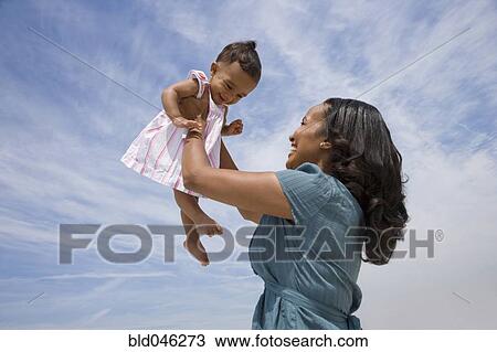 Stock Image - African American mother smiling at baby. Fotosearch