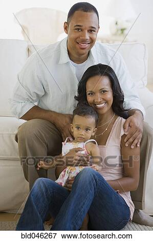 Stock Photo - African American parents and baby in living room. Fotosearch