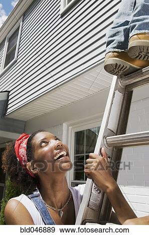 Stock Photo - African American woman holding ladder. Fotosearch