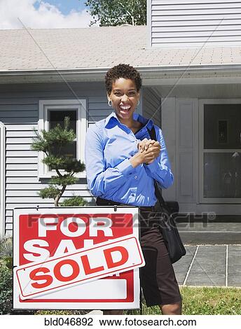 Stock Image - African American woman in front of new house. Fotosearch