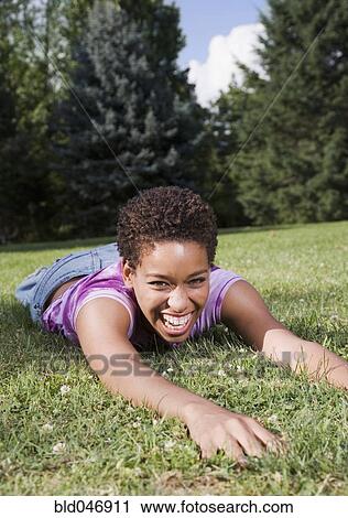 Stock Image - African American woman laying in grass. Fotosearch