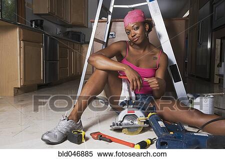 Stock Photography - African woman on floor with power tools. Fotosearch