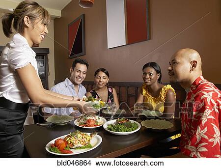 Picture - Asian female server bringing food to table. Fotosearch