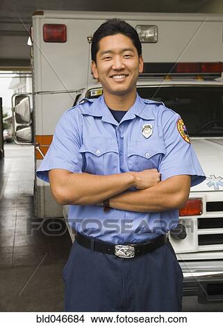 Picture - Asian male paramedic in front of ambulance. Fotosearch