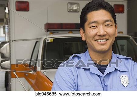 Stock Photography - Asian male paramedic in front of ambulance. Fotosearch