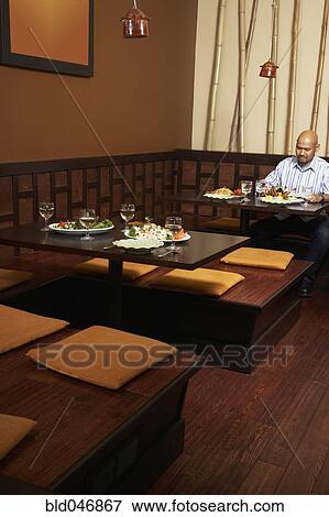Stock Photo - Asian man eating at restaurant. Fotosearch