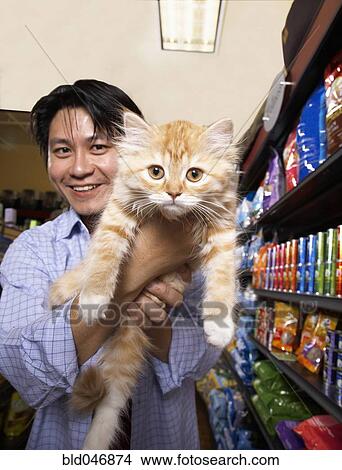 Picture - Asian man holding cat in pet store. Fotosearch