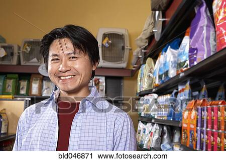 Stock Image - Asian man in pet store. Fotosearch