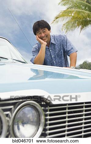 Stock Image - Asian man leaning on car. Fotosearch