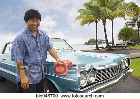 Stock Image - Asian man waxing car. Fotosearch