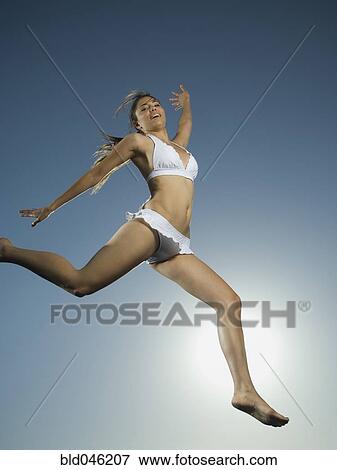 Stock Photo - Asian woman in bathing suit jumping. Fotosearch