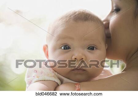 Hispanic baby looking over mother’s shoulder View Large Photo Image Stock Image - Hispanic baby looking over mother’s shoulder. Fotosearch