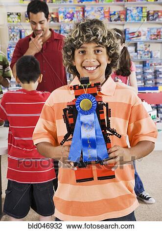 Stock Image - Hispanic boy holding toy with blue ribbon. Fotosearch