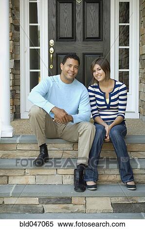 Stock Photography - Hispanic father and daughter sitting on porch steps. Fotosearch