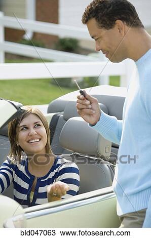Stock Image - Hispanic father giving daughter car key. Fotosearch