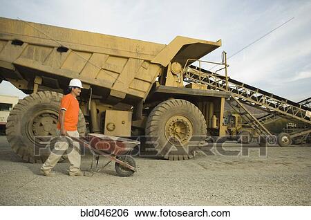 Hispanic man pushing wheelbarrow at gravel plant View Large Photo Image Stock Photograph - Hispanic man pushing wheelbarrow at gravel plant. Fotosearch