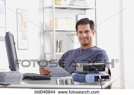 Hispanic man sitting at desk View Large Photo Image Picture - Hispanic man sitting at desk. Fotosearch