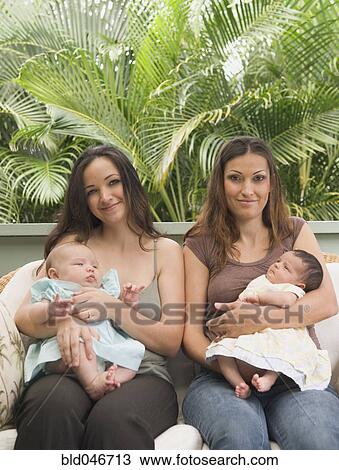 Stock Image - Hispanic mothers holding babies. Fotosearch