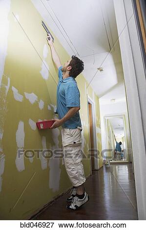 Middle Eastern man spackling wall View Large Photo Image Stock Photo - Middle Eastern man spackling wall. Fotosearch