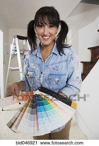 Stock Image - Middle Eastern woman holding paint swatches. Fotosearch