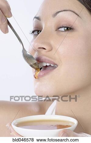 Stock Photo - Mixed Race woman dripping honey on lips. Fotosearch