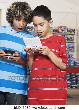 Multi-ethnic boys playing handheld video games View Large Photo Image Picture - Multi-ethnic boys playing handheld video games. Fotosearch