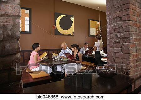 Stock Photo - Multi-ethnic friends at restaurant. Fotosearch